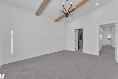 Empty room featuring suspended lighting, light colored carpet, and lofted ceiling - 38 Grayson Green, Stony Plain, AB - Indoor Photo Showing Other Room