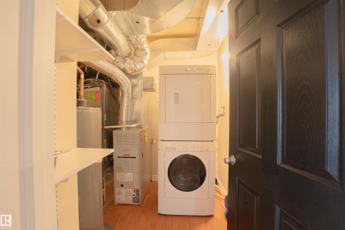 Washroom with stacked washer / dryer, light wood-style floors, and heating unit - 2953 26 Street, Edmonton, AB - Indoor Photo Showing Laundry Room