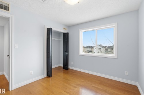 Unfurnished bedroom with a textured ceiling, a closet, and light wood-style flooring - 2953 26 Street, Edmonton, AB - Indoor Photo Showing Other Room