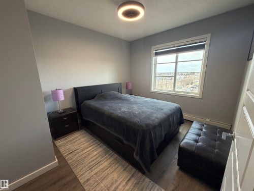 Bedroom with wood finished floors, a baseboard radiator, and a textured ceiling - 417 1004 Rosenthal Boulevard, Edmonton, AB - Indoor Photo Showing Bedroom