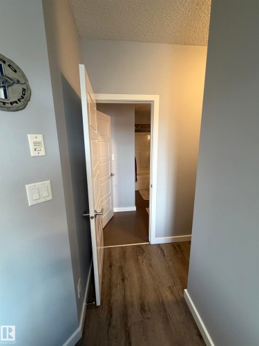 Hall with dark wood-style floors and a textured ceiling - 417 1004 Rosenthal Boulevard, Edmonton, AB - Indoor Photo Showing Other Room