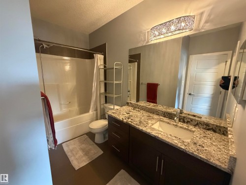 Full bath featuring vanity, a textured ceiling, and shower / bath combo - 417 1004 Rosenthal Boulevard, Edmonton, AB - Indoor Photo Showing Bathroom
