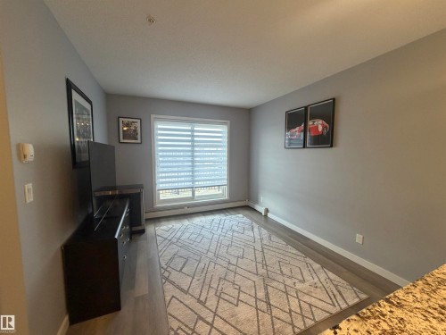 Unfurnished living room featuring a baseboard heating unit and light wood-style floors - 417 1004 Rosenthal Boulevard, Edmonton, AB - Indoor Photo Showing Other Room