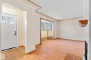 Foyer entrance with a textured ceiling, a large fireplace, and light wood-style flooring - 12232 135 Street, Edmonton, AB  - Indoor Photo Showing Other Room 