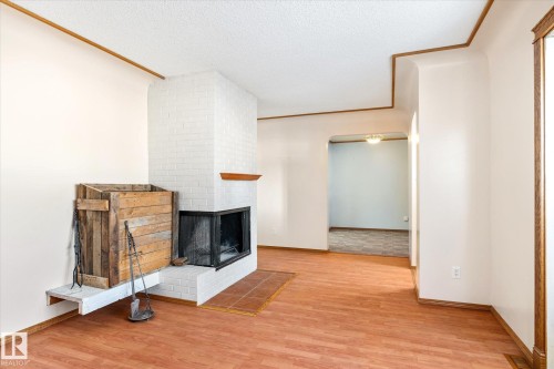 Unfurnished living room featuring a textured ceiling, light wood finished floors, and a fireplace - 12232 135 Street, Edmonton, AB - Indoor Photo Showing Other Room With Fireplace