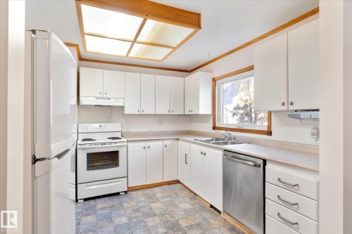 Kitchen with white appliances, white cabinetry, and light countertops - 12232 135 Street, Edmonton, AB - Indoor Photo Showing Kitchen With Double Sink