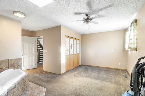 Empty room featuring carpet, a textured ceiling, and a ceiling fan - 12232 135 Street, Edmonton, AB - Indoor