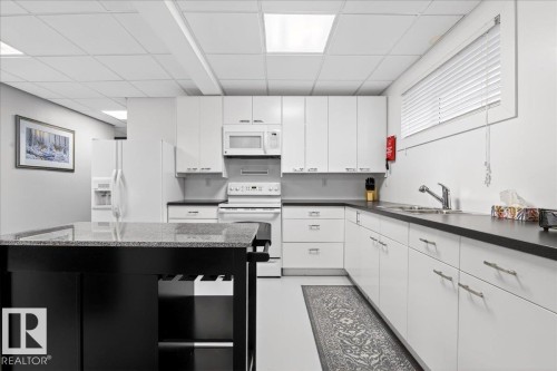 Kitchen with white appliances, a drop ceiling, and white cabinets - 5019 48 Avenue, Chipman, AB - Indoor Photo Showing Kitchen With Double Sink
