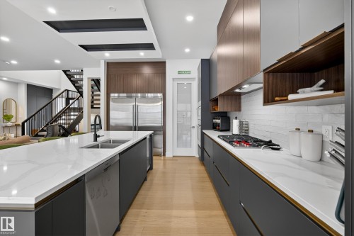 Kitchen with open shelves, light stone countertops, light wood finished floors, stainless steel appliances, and a spacious island - 1132 Wahl Place, Edmonton, AB - Indoor Photo Showing Kitchen With Double Sink With Upgraded Kitchen