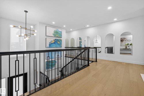 Hall with an upstairs landing, hanging lights, light wood-type flooring, and arched walkways - 1132 Wahl Place, Edmonton, AB - Indoor Photo Showing Other Room