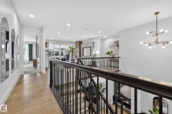 Hallway with an upstairs landing, hanging lights, and light wood-style flooring - 