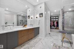 Full bath featuring a walk in closet, a marble finish shower, double vanity, recessed lighting, and light marble finish flooring - 