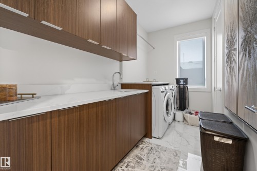 Laundry room featuring cabinet space, light marble finish floors, and washer and clothes dryer - 1132 Wahl Place, Edmonton, AB - Indoor Photo Showing Laundry Room