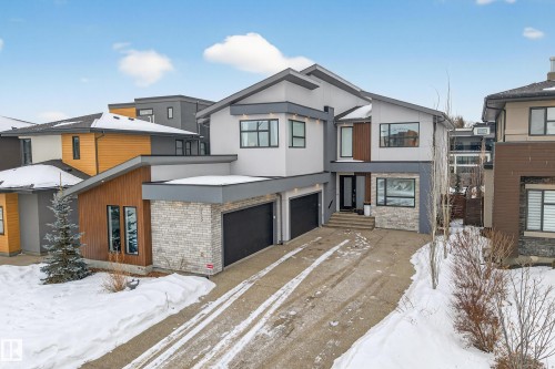 Contemporary home featuring brick siding, an attached garage, stucco siding, driveway, and a residential view - 1132 Wahl Place, Edmonton, AB - Outdoor With Facade