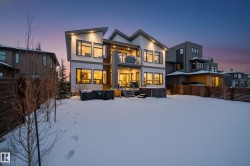 Snow covered rear of property with a fenced backyard, a hot tub, stucco siding, and a balcony - 