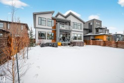 Snow covered house featuring stucco siding, a balcony, and a hot tub - 