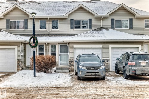 Traditional home with stone siding, a shingled roof, driveway, and a garage - 185 230 Edwards Drive, Edmonton, AB - Outdoor With Facade