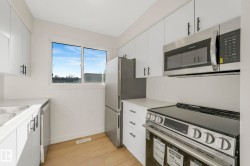 Kitchen featuring stainless steel appliances, light wood-style floors, and white cabinets - 