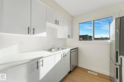 Kitchen with light countertops, appliances with stainless steel finishes, white cabinets, and light wood-style flooring - 