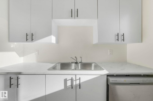 Kitchen with stainless steel dishwasher, white cabinets, light stone countertops, and modern cabinets - 5833 Riverbend Road, Edmonton, AB - Indoor Photo Showing Kitchen
