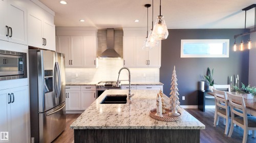 Kitchen featuring stainless steel appliances, light stone countertops, dark wood-style floors, and hanging light fixtures - 10 Moberg Close, Leduc, AB - Indoor Photo Showing Kitchen With Double Sink With Upgraded Kitchen