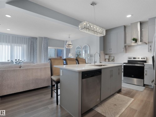 Kitchen featuring a kitchen breakfast bar, gray cabinets, open floor plan, stainless steel appliances, and decorative backsplash - 207 41 Avenue, Edmonton, AB - Indoor Photo Showing Kitchen