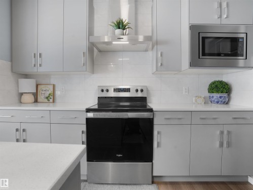 Kitchen featuring stainless steel appliances, decorative backsplash, light stone countertops, and light wood-style flooring - 207 41 Avenue, Edmonton, AB - Indoor Photo Showing Kitchen With Upgraded Kitchen