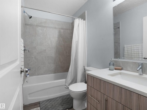 Full bathroom with shower / bath combo with shower curtain, vanity, and a textured ceiling - 207 41 Avenue, Edmonton, AB - Indoor Photo Showing Bathroom