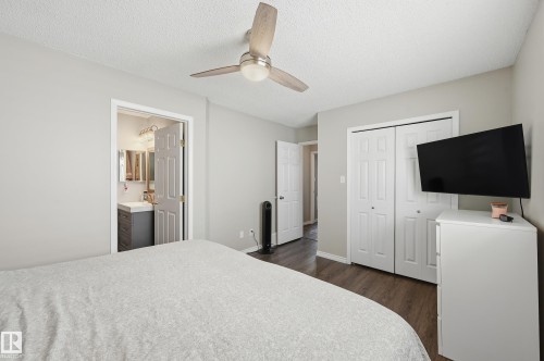 Bedroom with a closet, ceiling fan, dark wood-type flooring, a textured ceiling, and ensuite bathroom - 2952 39 Avenue, Edmonton, AB - Indoor Photo Showing Bedroom