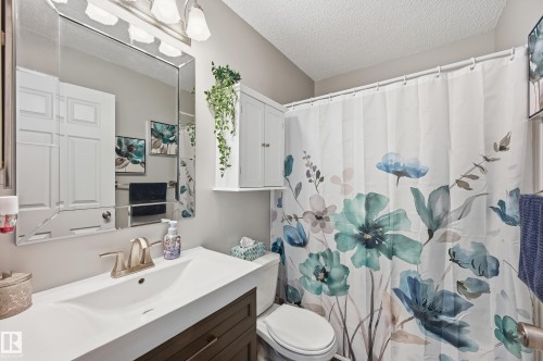 Full bath with a shower with curtain, vanity, and a textured ceiling - 2952 39 Avenue, Edmonton, AB - Indoor Photo Showing Bathroom
