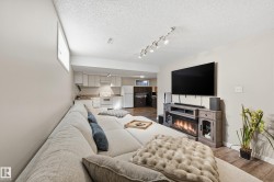 Living area with wood finished floors, track lighting, a textured ceiling, and a glass covered fireplace - 