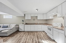 Kitchen featuring white appliances, white cabinets, light wood finished floors, and a textured ceiling - 