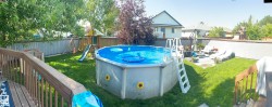 View of swimming pool with a playground, a fenced backyard, a wooden deck, and patio surround - 