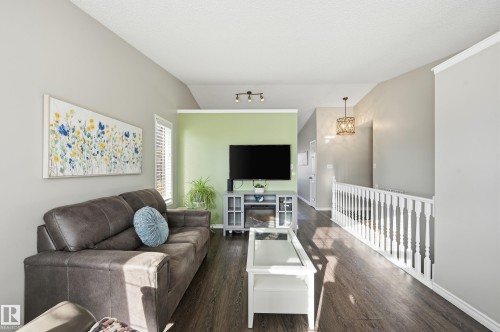 Living area featuring lofted ceiling, dark wood-style floors, and hanging lights - 2952 39 Avenue, Edmonton, AB - Indoor Photo Showing Living Room