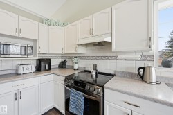 Kitchen featuring stainless steel appliances, white cabinetry, and light countertops - 