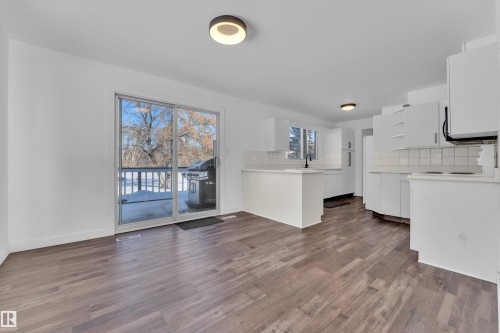 Kitchen featuring open shelves, light countertops, white cabinetry, backsplash, and dark wood-type flooring - 20920 9 Avenue, Edmonton, AB - Indoor Photo Showing Kitchen