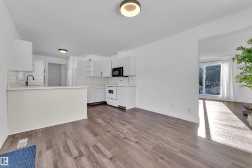 Kitchen featuring light countertops, open shelves, white cabinetry, electric range, and decorative backsplash - 20920 9 Avenue, Edmonton, AB - Indoor Photo Showing Kitchen