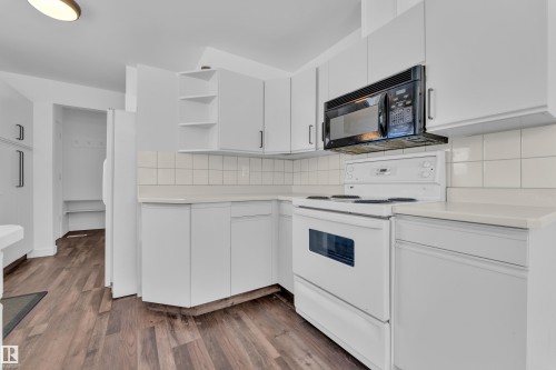 Kitchen featuring open shelves, white appliances, white cabinetry, light countertops, and dark wood finished floors - 20920 9 Avenue, Edmonton, AB - Indoor Photo Showing Kitchen