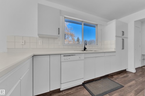 Kitchen with dishwasher, light countertops, white cabinets, backsplash, and dark wood-style floors - 20920 9 Avenue, Edmonton, AB - Indoor Photo Showing Kitchen