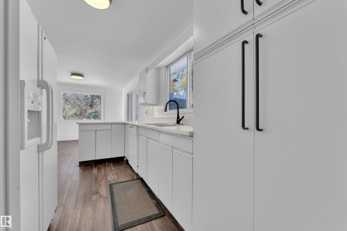 Kitchen featuring white appliances, white cabinets, and dark wood-style floors - 20920 9 Avenue, Edmonton, AB - Indoor
