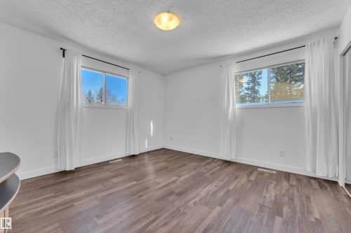 Unfurnished room with dark wood-style floors, a textured ceiling, and healthy amount of natural light - 20920 9 Avenue, Edmonton, AB - Indoor Photo Showing Other Room