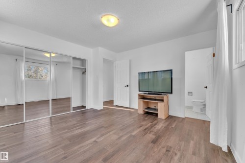 Unfurnished bedroom featuring a closet, wood finished floors, a textured ceiling, and ensuite bath - 20920 9 Avenue, Edmonton, AB - Indoor