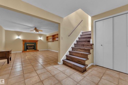 Stairs featuring a glass covered fireplace, tile patterned floors, and ceiling fan - 20920 9 Avenue, Edmonton, AB - Indoor Photo Showing Other Room With Fireplace