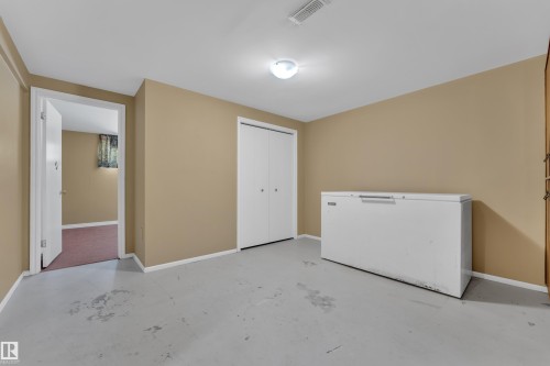 Unfurnished bedroom with concrete floors, a closet, and white refrigerator - 20920 9 Avenue, Edmonton, AB - Indoor