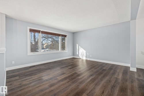 Spare room with dark wood-type flooring and a textured ceiling - 14911 96 Street, Edmonton, AB - Indoor With Fireplace