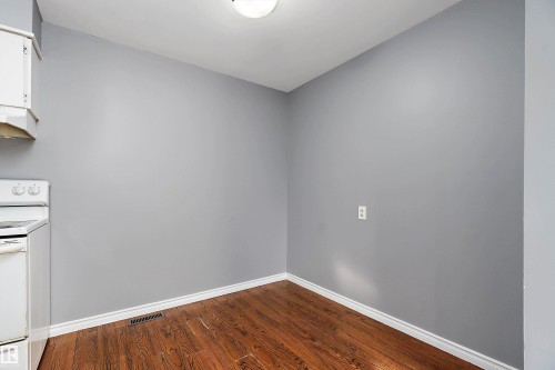 Empty room with baseboards and dark wood-style flooring - 15C Callingwood Crest, Edmonton, AB - Indoor Photo Showing Other Room