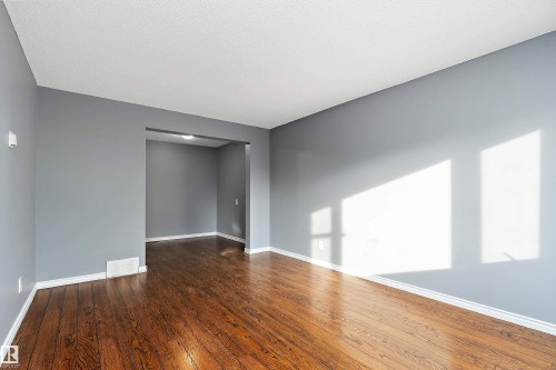 Unfurnished room with baseboards and dark wood-style floors - 15C Callingwood Crest, Edmonton, AB - Indoor Photo Showing Other Room