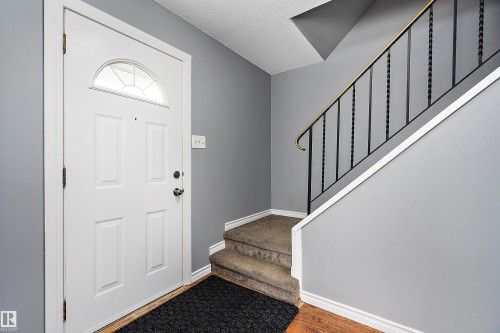 Foyer entrance with a textured ceiling and wood finished floors - 15C Callingwood Crest, Edmonton, AB - Indoor Photo Showing Other Room