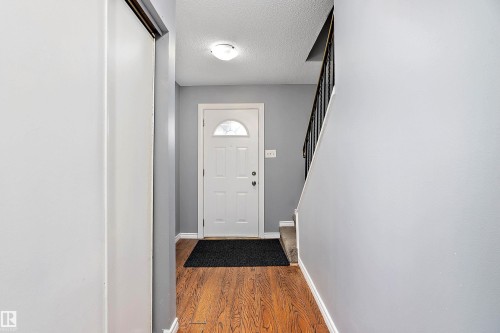 Doorway with a textured ceiling and wood finished floors - 15C Callingwood Crest, Edmonton, AB - Indoor Photo Showing Other Room