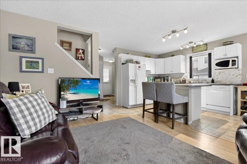 Living area featuring light wood-type flooring and a textured ceiling - 23 4020 21 Street, Edmonton, AB - Indoor